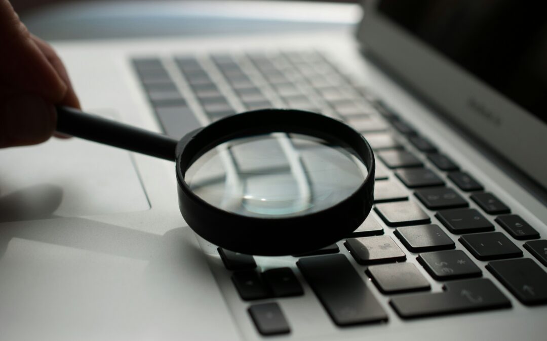 magnifying glass near gray laptop computer